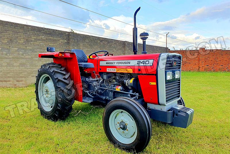 Roter Massey Ferguson 240 Traktor auf einer grünen Wiese vor einer Mauer.