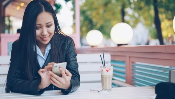 Frau prüft ihr Smartphone im Café neben einem Getränk