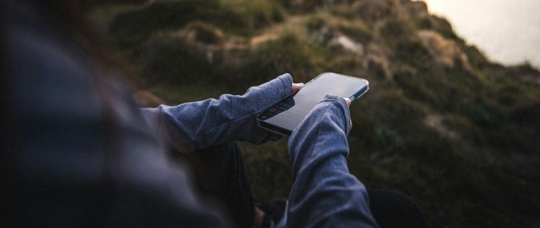 Person hält draußen ein Smartphone und prüft möglicherweise den Mobilfunkempfang