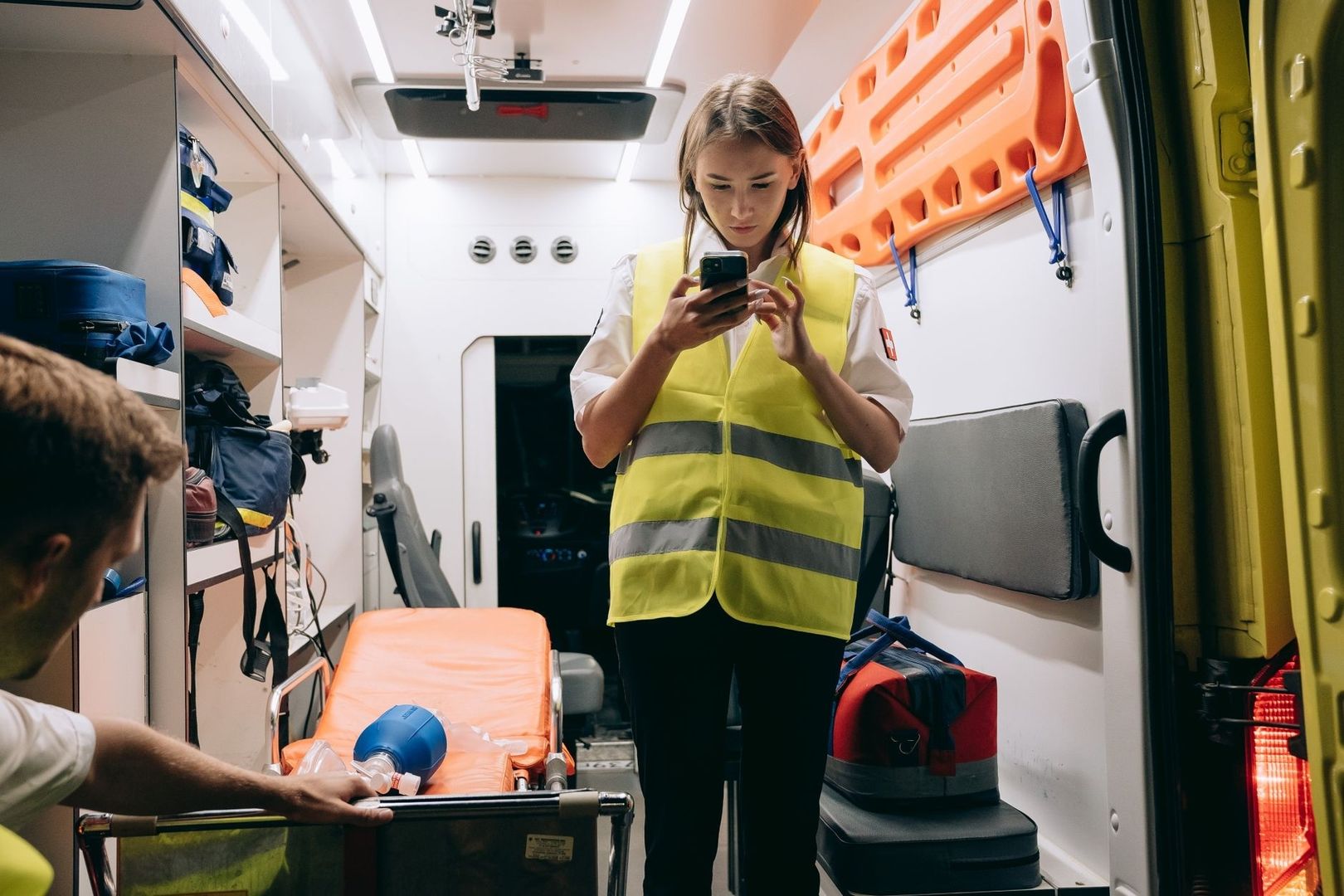 Mitarbeiterin im Rettungswagen nutzt ein Smartphone im Einsatz