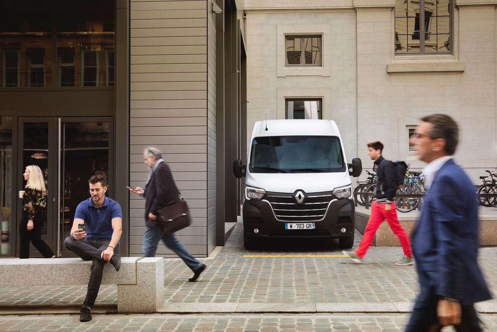 Weißer Service-Transporter vor einem Gebäude mit vorbeigehenden Passanten